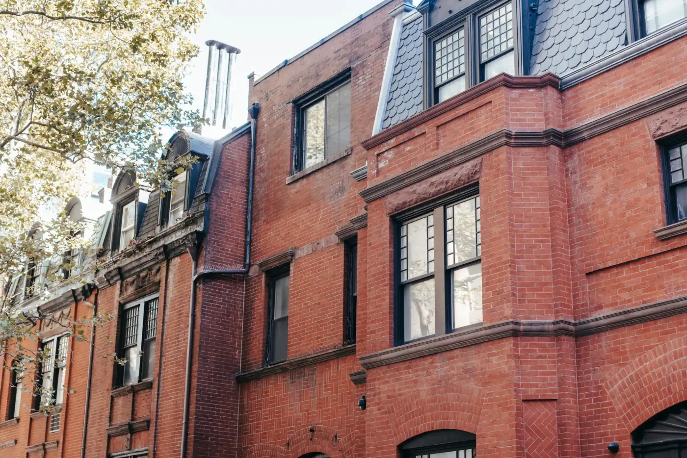 Older brick two-family buildings with dormers and stone sills along a residential street