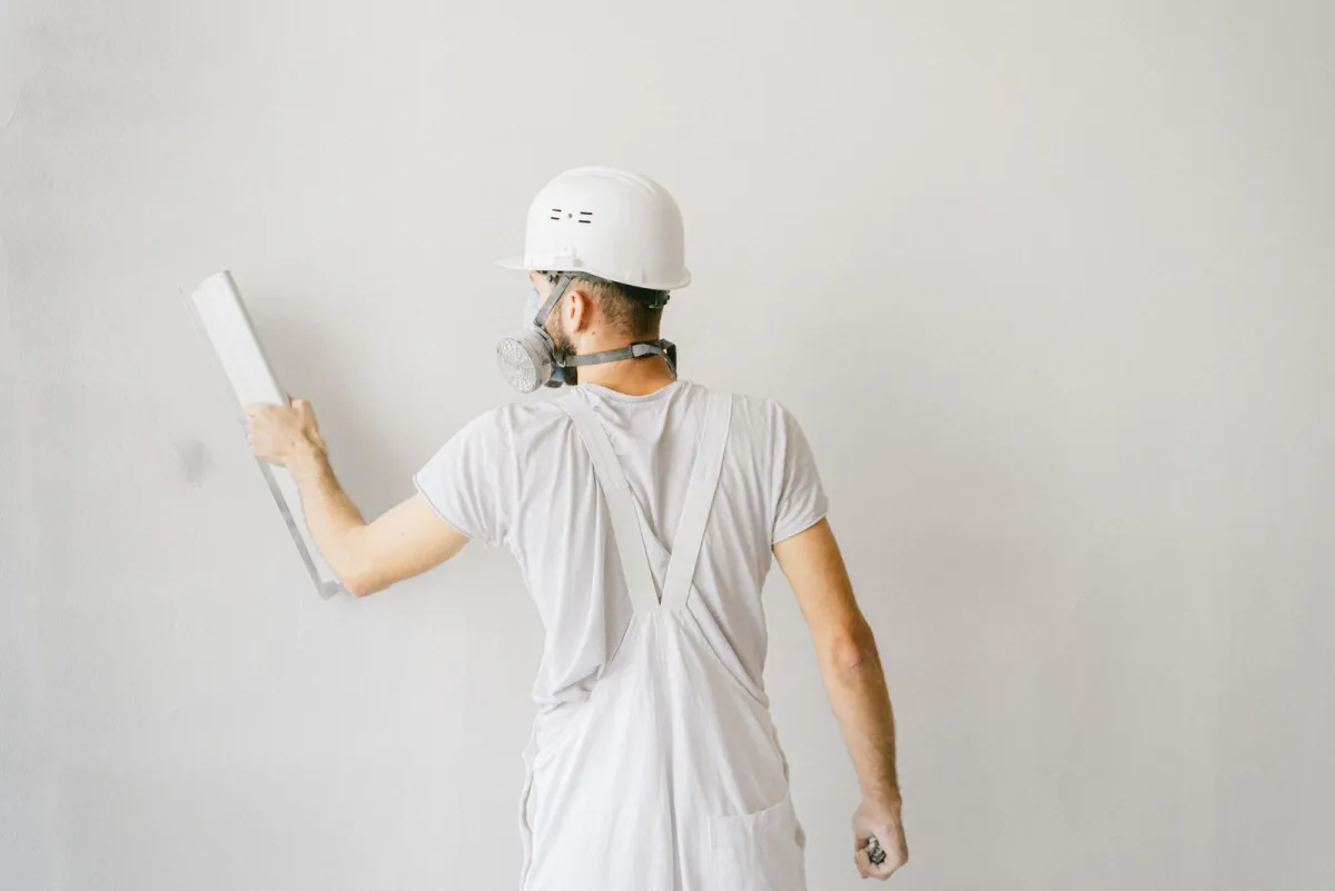 Drywall finisher drawing a wide blade across a skim coat on a wall