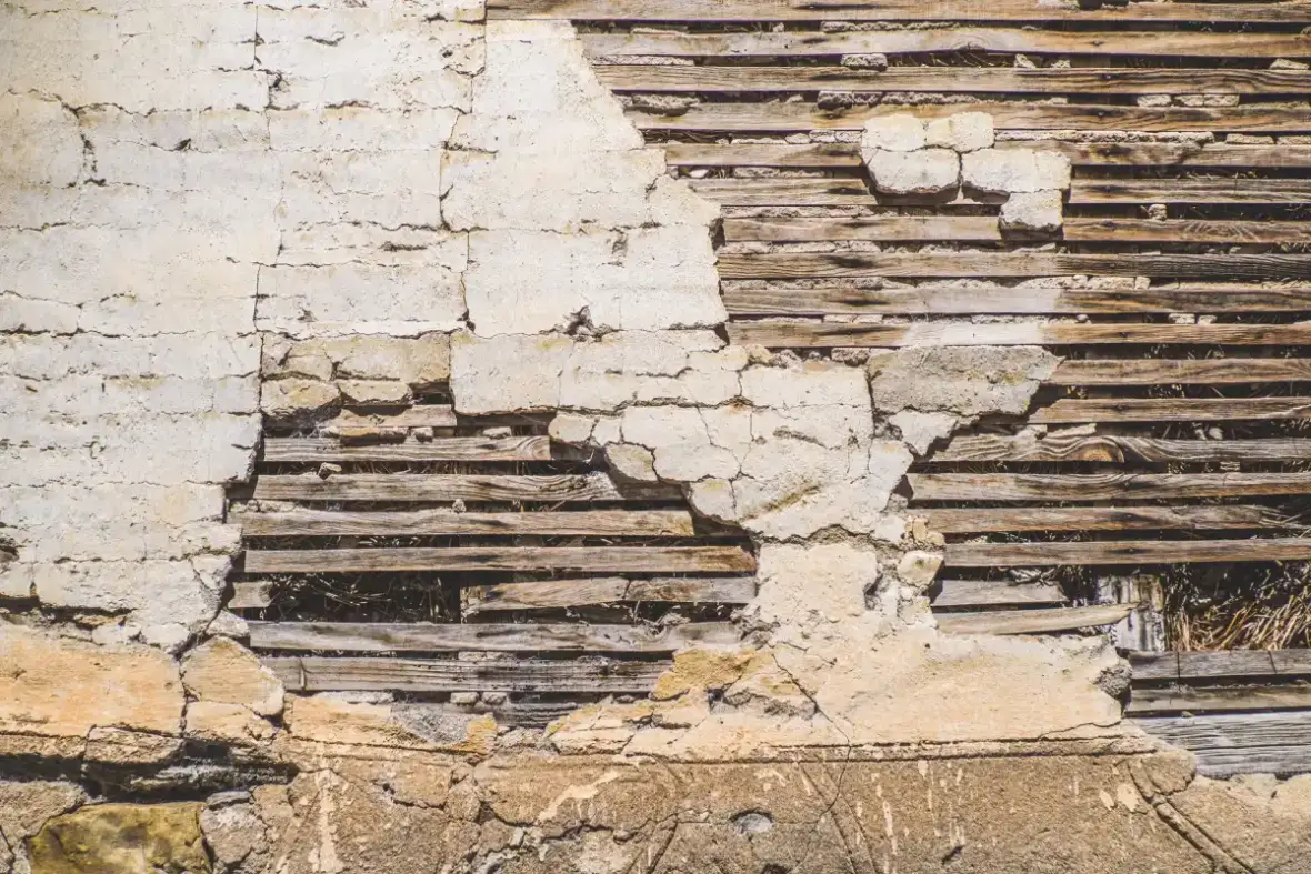 Wood lath exposed behind failed plaster on an older wall